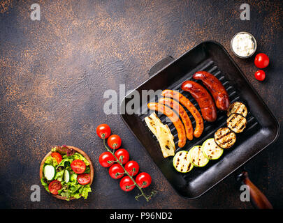 Sortiment von gegrillten Würstchen und Gemüse in Grillpfanne Stockfoto