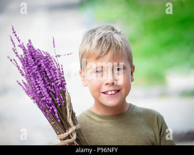 Süße blonde Junge mit Lavendel in den Händen Stockfoto