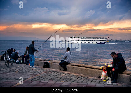 Izmir, Türkei - 28. Oktober 2017: VIEV von Izmir Alsancak Fähre und einige Männer angeln in der Nähe von Waters Edge mit bewölktem Wetter. Stockfoto