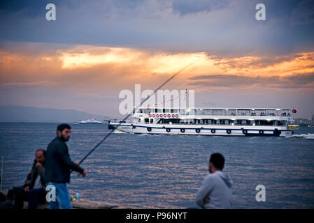 Izmir, Türkei - 28. Oktober 2017: VIEV von Izmir Alsancak Fähre und einige Männer angeln in der Nähe von Waters Edge mit bewölktem Wetter. Stockfoto