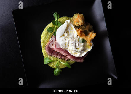 Thunfisch Steak mit Burrata Mozzarella, Zucchini Blumen, auf Zucchini Sauce gelegt, Ansicht von oben. Stockfoto