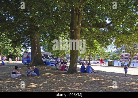 Menschen sitzen unter einem Baum an einem heißen Tag neben der Themse in Marlow, Buckinghamshire, England, Großbritannien