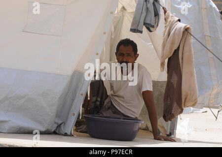 Sanaa, Jemen. Am 15. Juli 2018. Eine jemenitische Vertriebene Mann, der seine Heimat flohen in Hodeidah sitzt in seinem Zelt an einem vertriebenen Camp in Sanaa, Jemen, am 15. Juli 2018. Mehr als 121.000 Bewohner haben den Krieg zerrissenen Stadt Hodeidah und andere Teile der Provinz flohen seit dem 1. Juni, die Vereinten Nationen in dieser Woche sagte. Credit: Mohammed Mohammed/Xinhua/Alamy leben Nachrichten Stockfoto