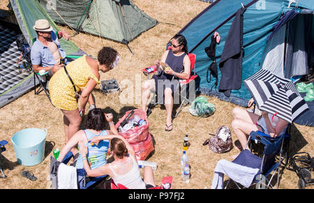 Festivalbesucher entspannend neben Zelten, in dem Campingplatz bei Latitude Festival, henham Park, Suffolk, England, 15. Juli 2018 Stockfoto