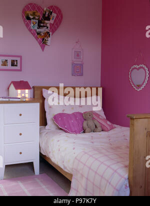 Blumen Kopfkissen und Bettdecke mit überprüften werfen auf einfache Kiefer Bett in rosa Schlafzimmer des Kindes Stockfoto