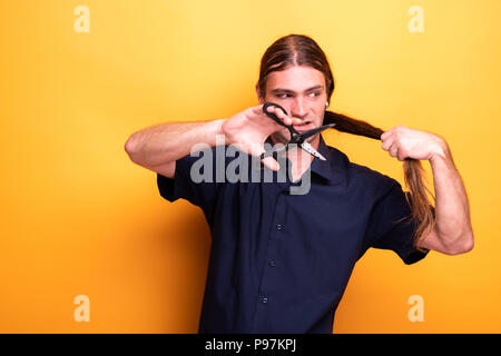 Zornigen Mann beschlossen, seine langen Haare mit der Schere schneiden Stockfoto