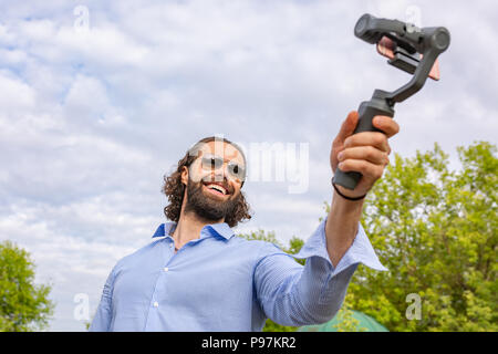 Kerl mit dem Telefon auf dem Stabilisator, nimmt er sich selbst zur Kamera Smartphone Kamera Stockfoto