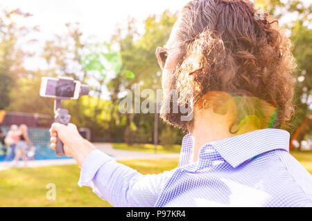 Kerl mit dem Telefon auf dem Stabilisator, nimmt er sich selbst zur Kamera Smartphone Kamera Stockfoto