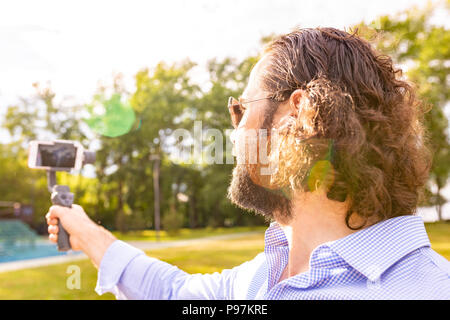 Kerl mit dem Telefon auf dem Stabilisator, nimmt er sich selbst zur Kamera Smartphone Kamera Stockfoto