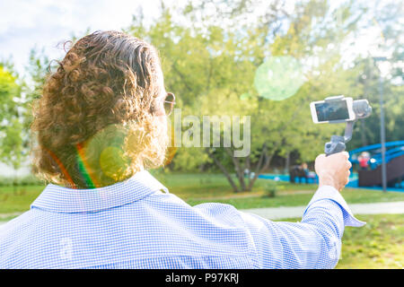 Kerl mit dem Telefon auf dem Stabilisator, nimmt er sich selbst zur Kamera Smartphone Kamera Stockfoto