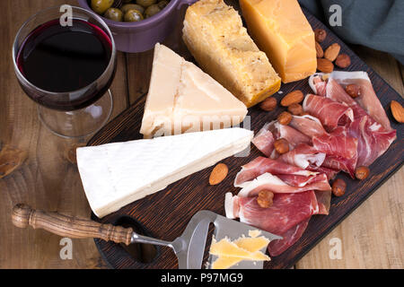 Verschiedene Käse, Fleisch, Wein in ein Glas und Oliven. Eine köstliche italienische Snack für eine Party. Blick von oben. Platz kopieren Stockfoto