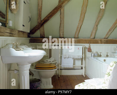 Weißen Sockel Waschbecken und Toilette mit Sitz in einem Land, Badezimmer mit Balkendecke Stockfoto