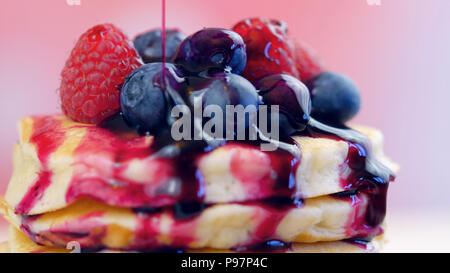 Der Pfannkuchen mit Himbeeren, Heidelbeeren Stack und mit blueberry Ahornsirup beträufelt, Makro Nahaufnahme. Stockfoto