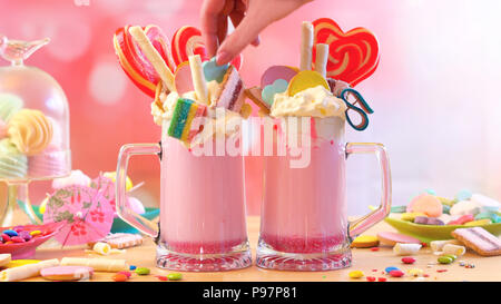 Making modern Trend Erdbeere freak shakes Milchshakes toppping mit Lutscher Bonbons und Kekse, selektiven Fokus. Stockfoto