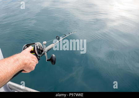 Erwartung fängt einen Fisch: des Menschen Hand mit Angelrute Pol mit Linie im Meer Wasser im Far North Distrikt, Northland, Neuseeland, NZ Stockfoto