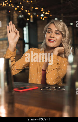 Tipsy junge Frau winkt für jemand in bar Stockfoto