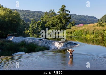 Ein Schwimmer in den Untiefen der Vorbereitung in den Fluss Avon bei Warleigh Wehr in Somerset, England zu schwimmen. Stockfoto