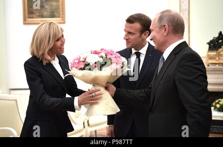 Moskau, Russland. 15. Juli 2018. Der russische Präsident Wladimir Putin, rechts, stellt Brigitte Längestrich mit Blumen vor der Begegnung mit ihrem Mann französische Präsident Emmanuel Längestrich, Mitte, im Kreml Juli 15, 2018 in Moskau, Russland. Längestrich wurde in Moskau das Finale in der Fußball-Weltmeisterschaft, die Frankreich 4-2 über Kroatien gewonnen zu besuchen. Credit: Planetpix/Alamy leben Nachrichten Stockfoto