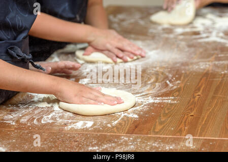 In der Nähe von Kinderhänden Zubereitung Teig für Pizza. Pizza, Kinder und das Konzept der Kochen - Kinder machen Pizza. Stockfoto