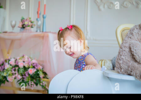 Kleine Mädchen spielen mit weißen Holzmöbeln Schaukelpferd und Bär Puppe Stockfoto