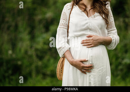 Schönheit schwangere Frau. Schwangeren Bauch. Schöne schwangere Frau posiert im Park. Stockfoto