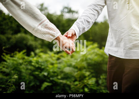 Glücklich und junge Schwangere Paar umarmen in der Natur. Schwangeren Paare ihre Zukunft baby boots Holding. Stockfoto