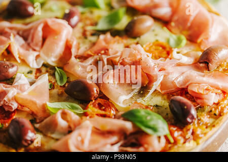 Nahaufnahme von appetitlich klassische traditionelle italienische Pizza mit Käse, Schinken und Gemüse auf rustikalen Textil. Ansicht von oben Stockfoto