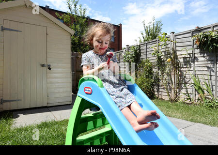 Ein junges Mädchen in einem Garten genießen Sie ein Eis in der Sonne in London, UK. Stockfoto