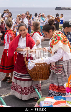 Ponta Delgada, Azoren, Portugal - 07/07/2018 - zwei junge Mädchen in traditioneller Kleidung, halten einen Weidenkorb - Göttliche Heilige Geist Feier Stockfoto