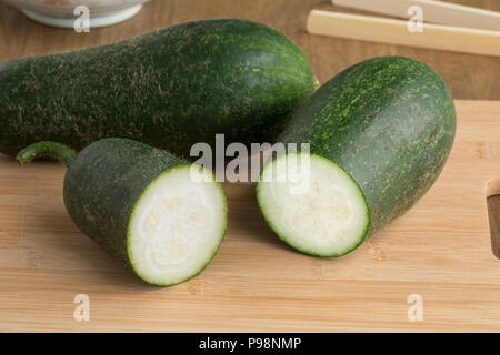 Paar frische rohe ganze und halbe haarige cucumberon ein Schneidebrett Stockfoto