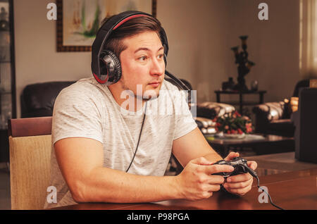 Konzentriert man die Videospiele spielen. Um Spiele zu Hause spielen Süchtig, Holding a video game Control und das Tragen eines Gamer Headset. Stockfoto