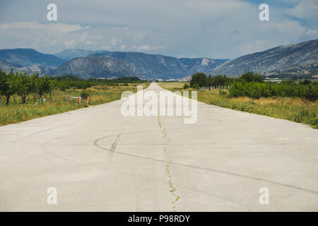 Die Suche nach einem ausgedienten Rollweg, jetzt eine öffentliche Straße, am Ortsrand von Flughafen Mostar, Bosnien und Herzegowina Stockfoto