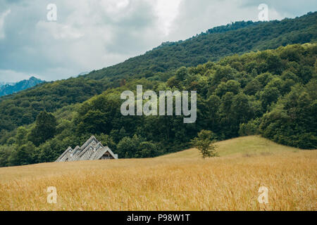 Die ungewöhnliche postmodernen dreieckige Linien der Spomen-Dom (Memory Haus) durch Ranko Radović Peek über ein Feld im Nationalpark Sutjeska, BiH Stockfoto