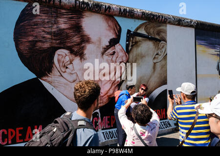 Berlin, Deutschland - Juli 2018: Touristen an der Berliner Mauer/East Side Gallery vor Dimitri Vrubel' Malerei posing - der die brüderliche Kuss (Germa Stockfoto