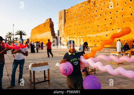 Rabat, Marokko: ein Junge Verkauf von Ballons Spaziergang, vorbei an den Überresten der Almohaden Hassan Turm und Moschee. Die größte in der Welt zu sein, es wa Stockfoto