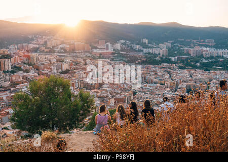 Eine junge Gruppe von Touristen sitzen auf Bunquers del Carmel bei Sonnenuntergang, einen berühmten Aussichtspunkt über die Stadt Barcelona, Spanien Stockfoto