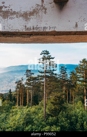 "Schau mal, bevor du springst", geschrieben auf einem Betonbalken im Bistrik Tower, einem verlassenen Fort auf dem Berg Trebević, Sarajevo Stockfoto