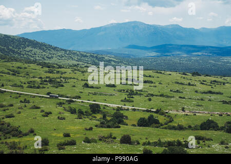 Ein einsamer Lastwagen fährt auf einer leeren Straße durch die bosnische Landschaft Stockfoto
