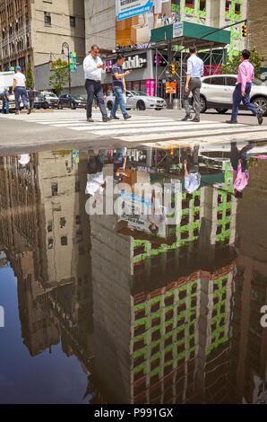 New York City, USA - Juni 28, 2018: die Menschen zu Fuß durch die Fußgängerzone überqueren in einer Pfütze in Midtown Manhattan nieder. Stockfoto