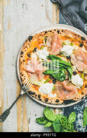 Frisch gebackene Pizza mit Schinken, Artischocken, Käse und Basilikum Stockfoto