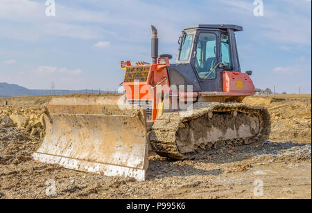 Rot schmutzig Bulldozer zu einem lehmigen Baustelle Stockfoto