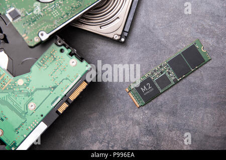 Moderne M.2 SSD-Laufwerk und alte Festplatten liegen auf einer Steinplatte Stockfoto