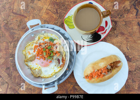 Nordöstliche thailändische Frühstück mit Kaffee, heiße Pfanne Spiegeleier Material mit gehacktem Schweinefleisch und Wurst, auch für Vietnam und Laos Menschen Stockfoto