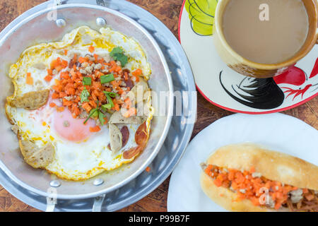 Nordöstliche thailändische Frühstück mit Kaffee, heiße Pfanne Spiegeleier Material mit gehacktem Schweinefleisch und Wurst, auch für Vietnam und Laos Menschen Stockfoto