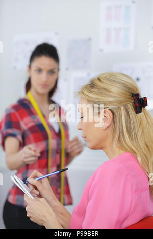 Nachdenklich ernsten Näherin Denken und Schreiben Notizen im Notebook Stockfoto