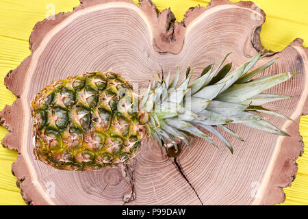 Frische Ananas auf natürlichem Holz. Ganze bio Ananas Obst auf Baumstumpf gelegt, Ansicht von oben. Gesunde exotische Speisen. Stockfoto