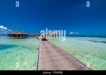 Malediven Insel, Luxus Water Villas Resort und hölzernen Pier. Schönen Himmel und Wolken und Strand Hintergrund für Sommer Urlaub und Reisen Stockfoto