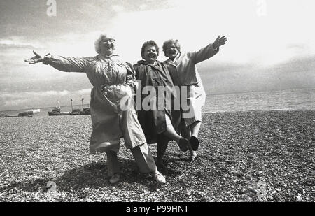 1970 s, drei ältere Damen Spaß - ein Knie - an einem Strand, auf einem Rentner Reise ans Meer, Hastings, East Sussex, West Sussex, England, UK. Stockfoto