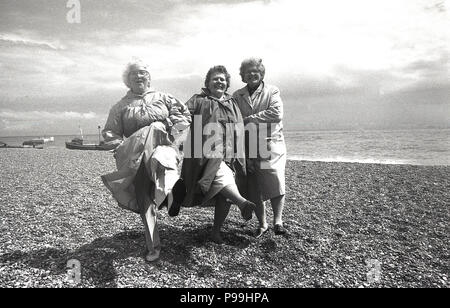 1970 s, drei ältere Damen Spaß - ein Knie - an einem Strand, auf einem Rentner Reise ans Meer, Hastings, East Sussex, West Sussex, England, UK. Stockfoto