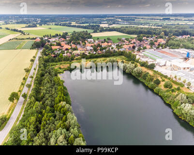 Luftaufnahme von einem kleinen deutschen Dorf hinter einem künstlichen See, der durch Sand Mining für eine konkrete Anlage, mit Drone, erstellt wurde. Stockfoto